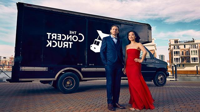 a woman in a red dress and a man in a suit stand in front of a black truck with the words the concert truck on it